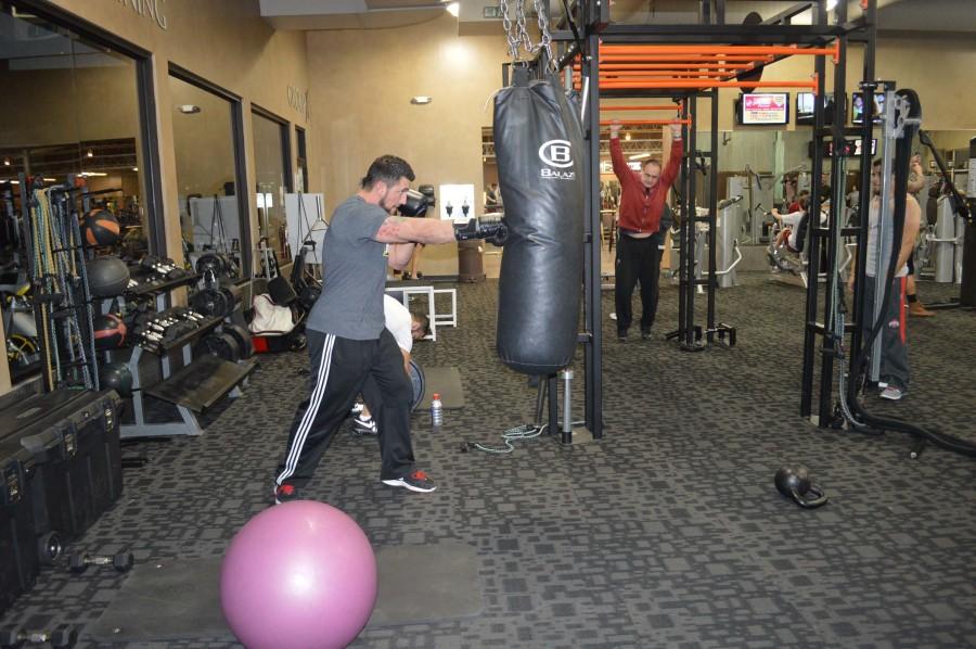 Campbell vigorously punches a punching bag while wearing boxing gloves. He squeezes his abdominal muscles while doing so, making sure to exhale when his fist hits the bag. This give his abdominal muscles a workout as well and his arm muscles. 