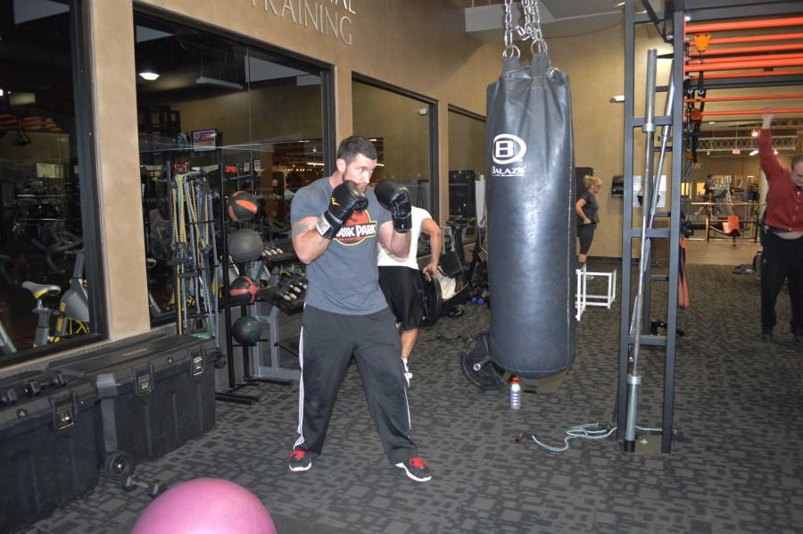Campbell vigorously punches a punching bag while wearing boxing gloves. He squeezes his abdominal muscles while doing so, making sure to exhale when his fist hits the bag. This give his abdominal muscles a workout as well and his arm muscles. 