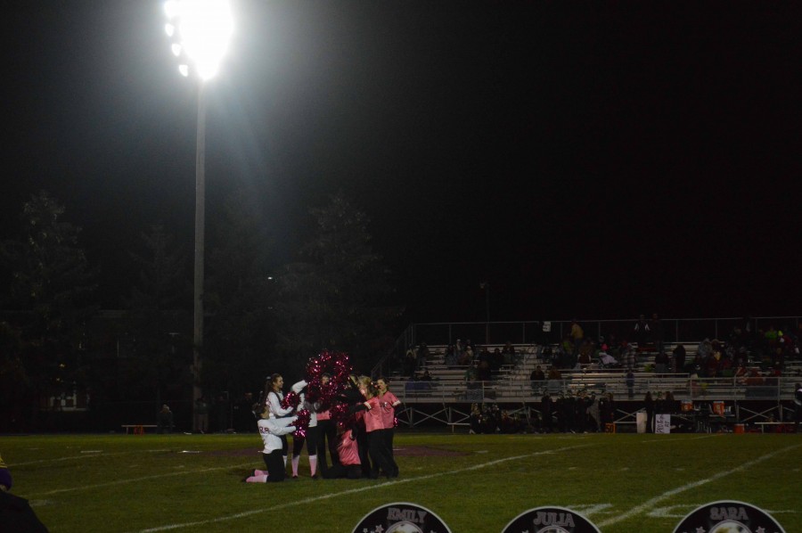 Poms team holds up a cancer ribbon to raise awareness about breast cancer. 