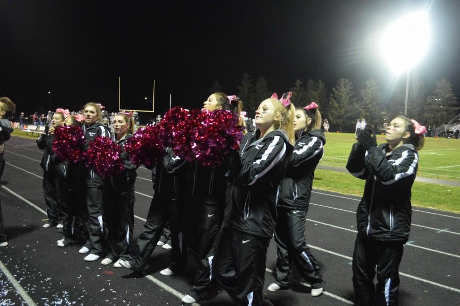 Varsity cheer team leads crowd in a chant. 