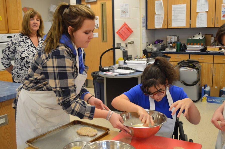 Hannah+King+and+Emma+Glennon+prepare+chicken+by+coating+it+with+breadcrumbs.+This+might+look+messy+now%2C+but+the+end+result+is+definitely+worth+it.+%0A