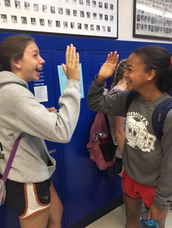 Sophomores Cassidy Motyka and Vanessa Theobald high five eachother for their spirit wear.