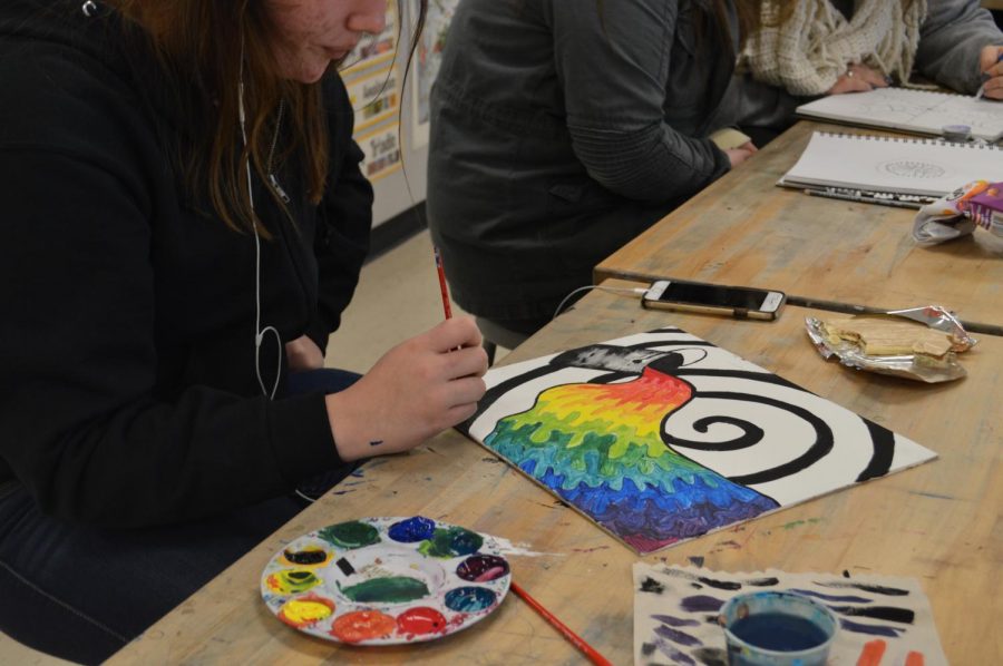 With her paint palette full of all different colors, sophomore Hannah McCarren finishes up her beautiful painting as she comfortably listens to music and has a snack. 