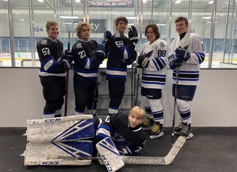 From left to right, junior Connor Rei, junior Andrew Olson, junior Brayden Farmer, sophomore Bud Leavey and freshman Easton Carriere stand behind senior goalie Bryce Wojtyszyn, all Kaneland students. On their shoulders is a patch with the Kaneland logo, which is how the players represent their schools while on the ice. 