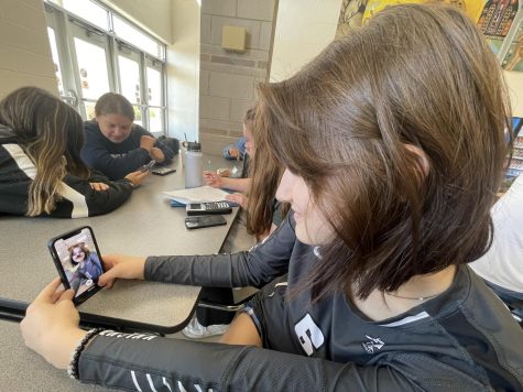 Sophomore Lilia Fleshman takes a selfie on Snapchat using the dog face filter. Around her, students of all grade levels talk with friends and scroll through social media.