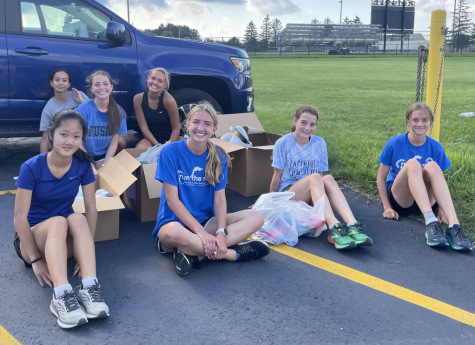 Members of the girls cross country team sit by boxes of donations for the Marklund Center. The boxes were filled with self-care items such as shampoo, conditioner and body wash.