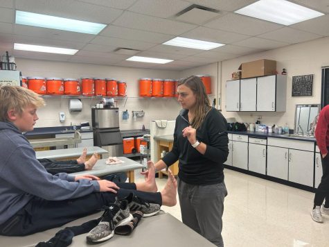 Athletic trainer Maggie Walker consults with sophomore basketball player Chase Kruckenberg. This year, ankle injuries are common for basketball players.