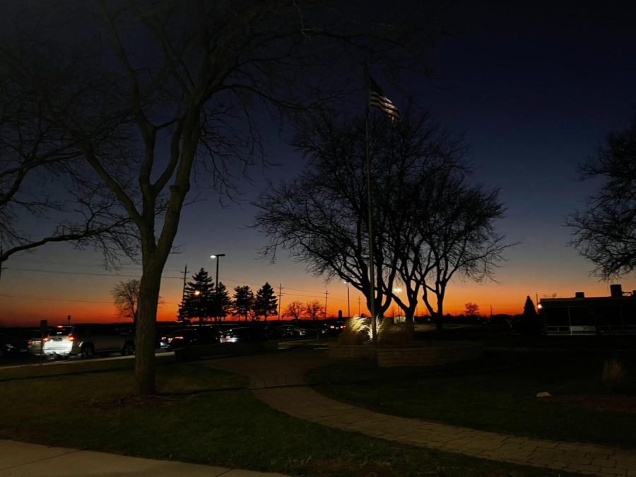 The trees are bare and the sun sets near the entrance of Kaneland High School. Parents have picked up their kids from their after-school activities and many students are ready to go home and sleep.