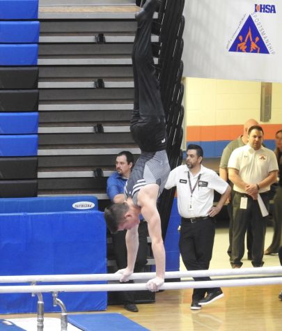 Senior Ethan Yost does a handstand on parallel bars at an IHSA gymnastics competition at Hoffman Estates High School
in 2022. Yost maintains a disciplined routine in order to have success in his many different extracurricular activities. (Photo courtesy of Ethan Yost)