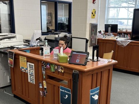 Librarian Jessica Parker sits at a desk that also functions as an e-pass station. The library is one of the most visited places in the school throughout the day. Teachers can give a student a pass so that Parker can check the student into the library.