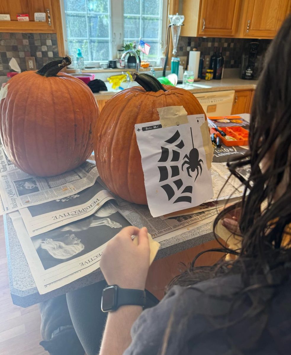 A student uses a template to carve out a design in a pumpkin. After carving pumpkins, there are many ways to reuse them, such as putting them in a compost bin or using the pulp to create a meal.