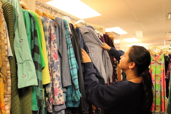 A customer looks for clothes to buy at a thrift store. Many people rely on thrift stores to access affordable clothing.
