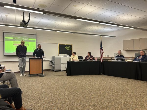 Head boys cross country coach Chad Clarey and senior Collin Reutimann share details about the boys cross country team’s successful season. Fall sports were honored at the board meeting, and many coaches and athletes came to share their successes.