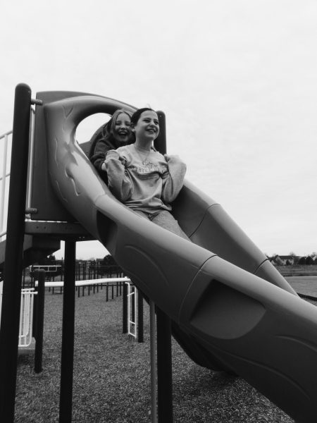 Two children go down a slide on a playground. In today's world, most kids' social interactions incorporate the use of technology, which could include playing online games, FaceTiming and making TikTok dance videos. 