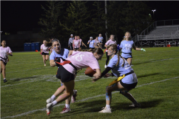 Junior and senior girls fight for the football in the powderpuff game on the Wednesday of Homecoming week. One of the junior players steals a flag off of the opposing team.