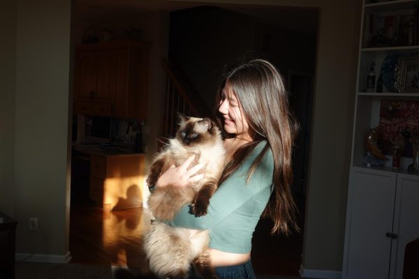 In a heartwarming moment, senior Jade Lee cuddles up to her cat, Poopie. Poopie is a ragdoll, and he is approximately five years old. Lee adopted him in 2021, and she notes that he is incredibly lazy and enjoys sleeping on computers to prevent her from getting tasks done.